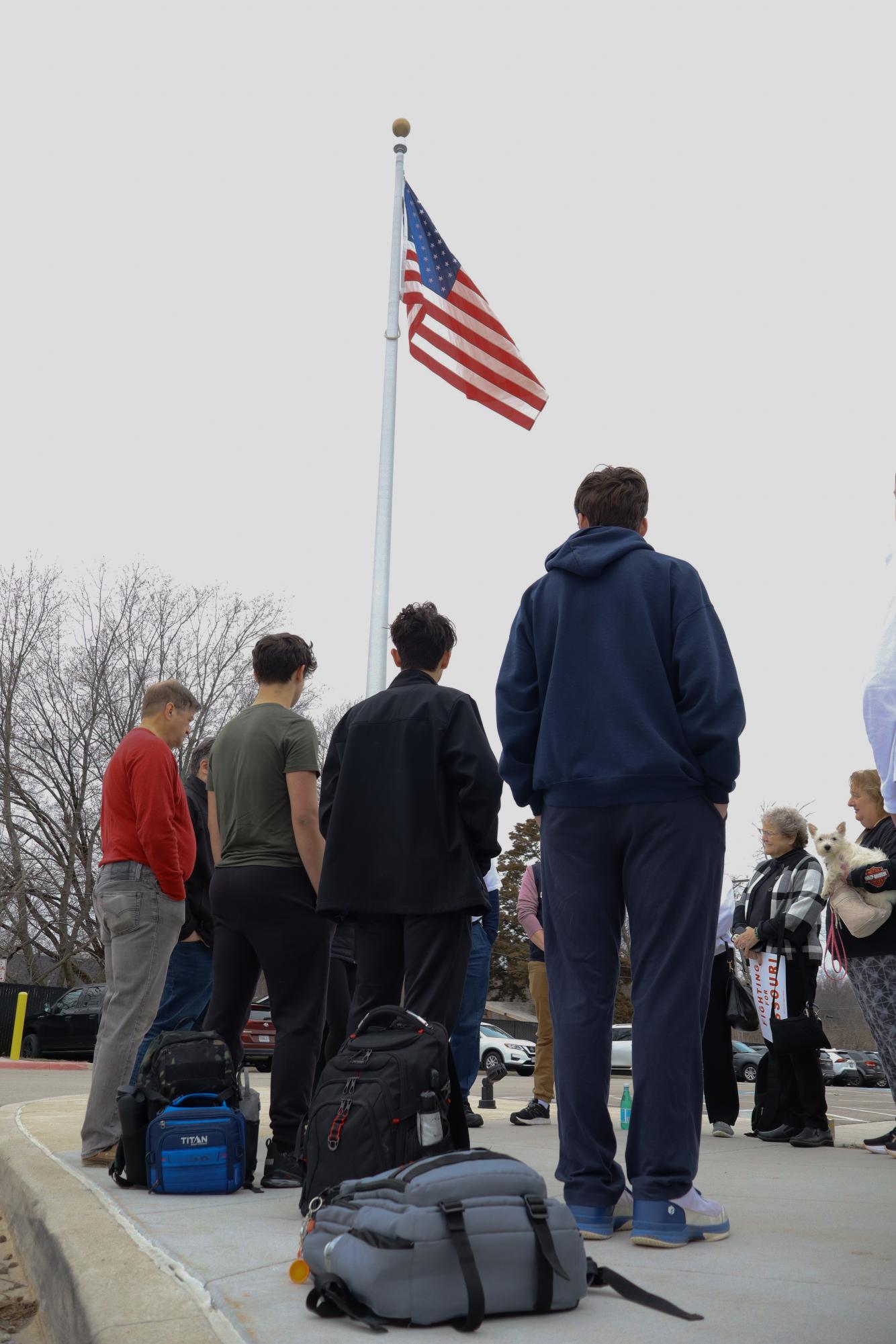 Club America members, along with adults stand in a circle by the flagpole. Photo by Coy Ruehter. 
