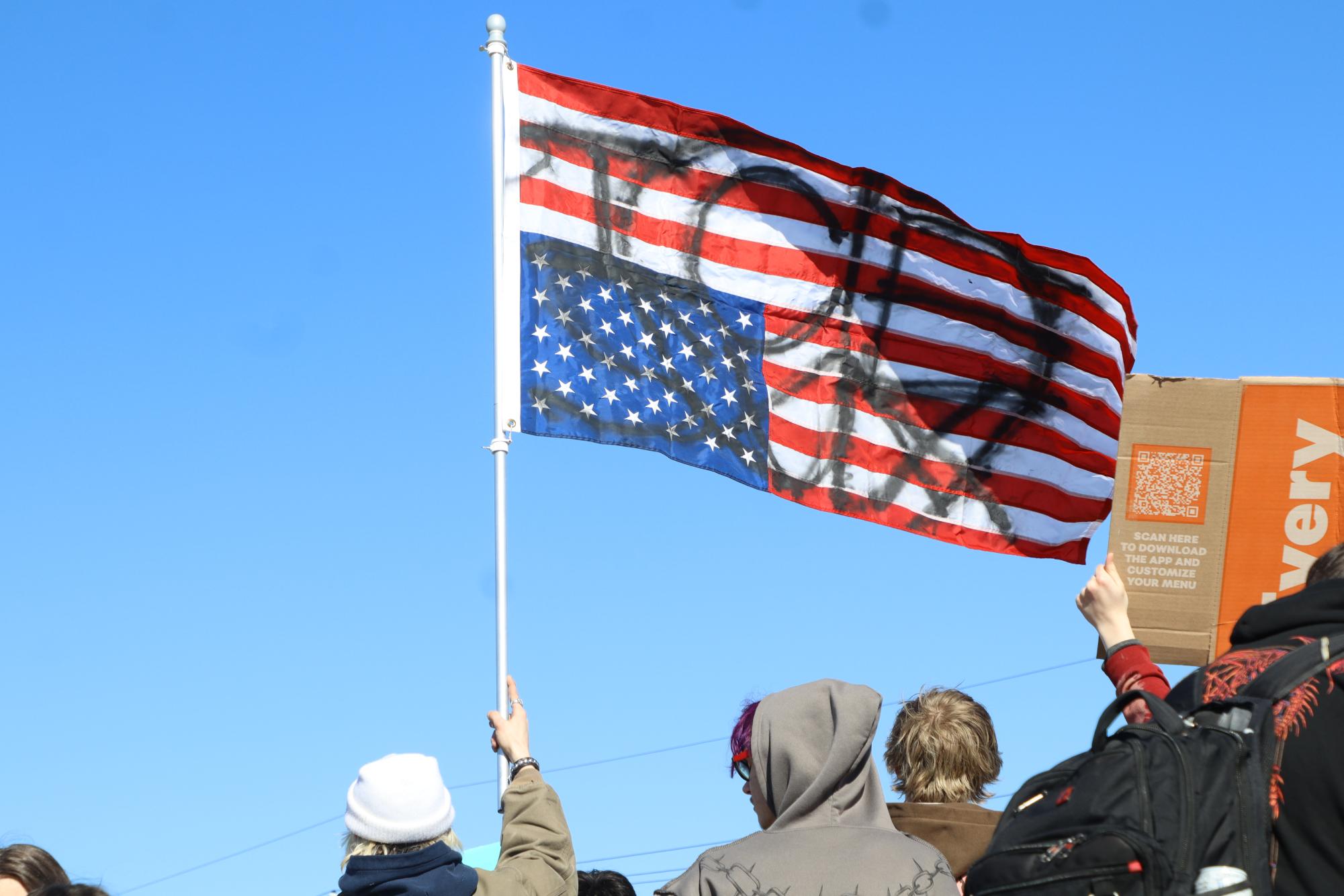 Peace: Students at the LSHS Ice protest raise an American flag that displays a peace sign. 